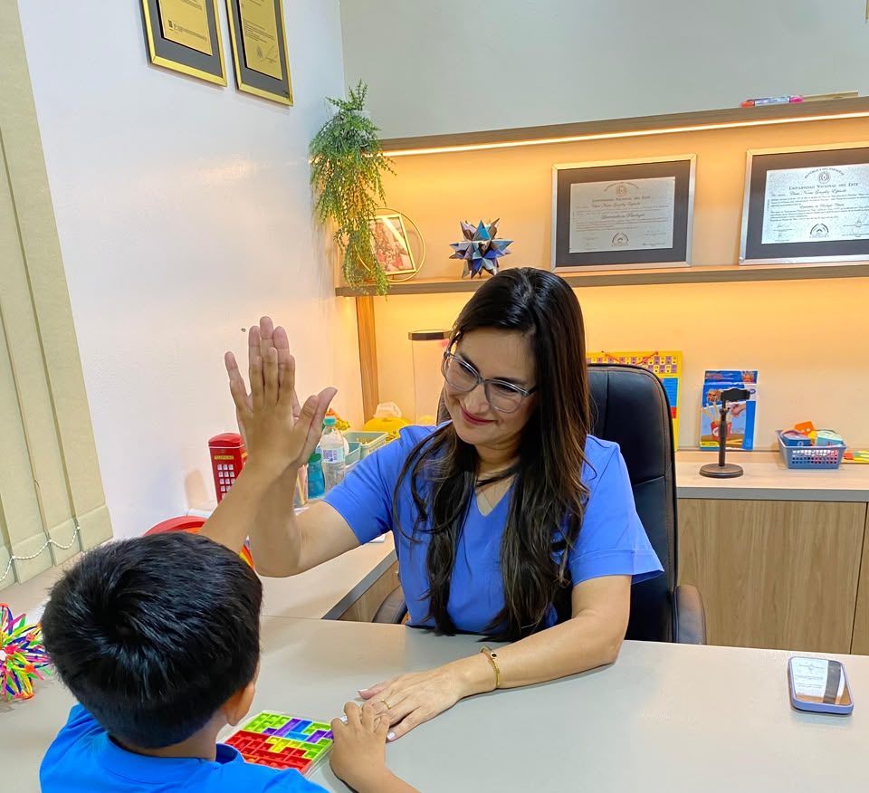 En uno de nuestros consultorios, una terapeuta choca los cinco con un niño que está de espaldas a la cámara