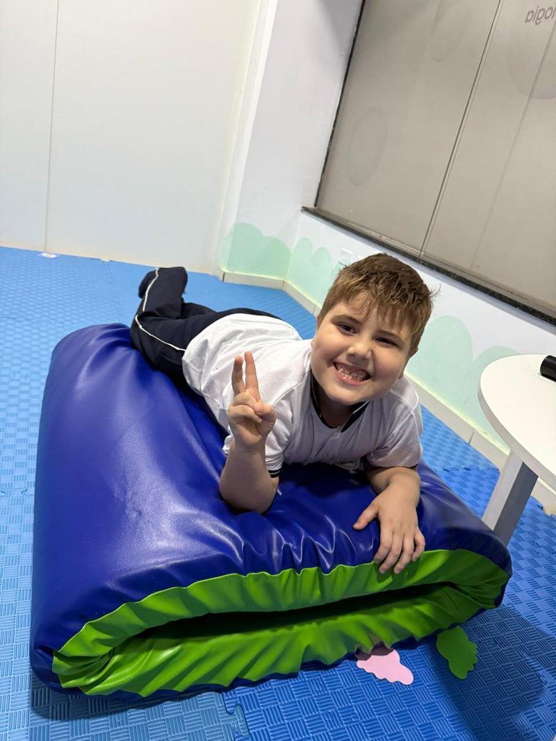 Un niño sonríe recostado sobre un puff azul y verde en la sala de la clínica
