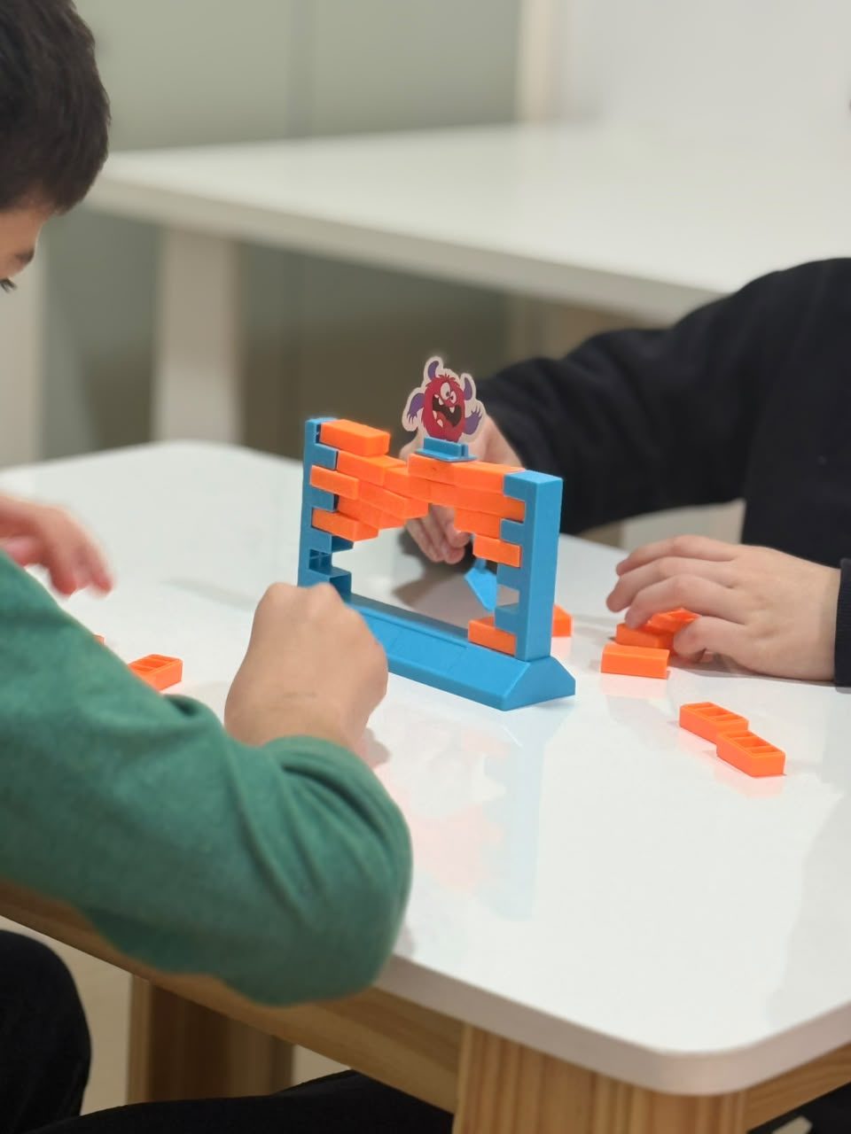 Dos niños concentrados en un juego de bloques sobre la mesa de la sala
