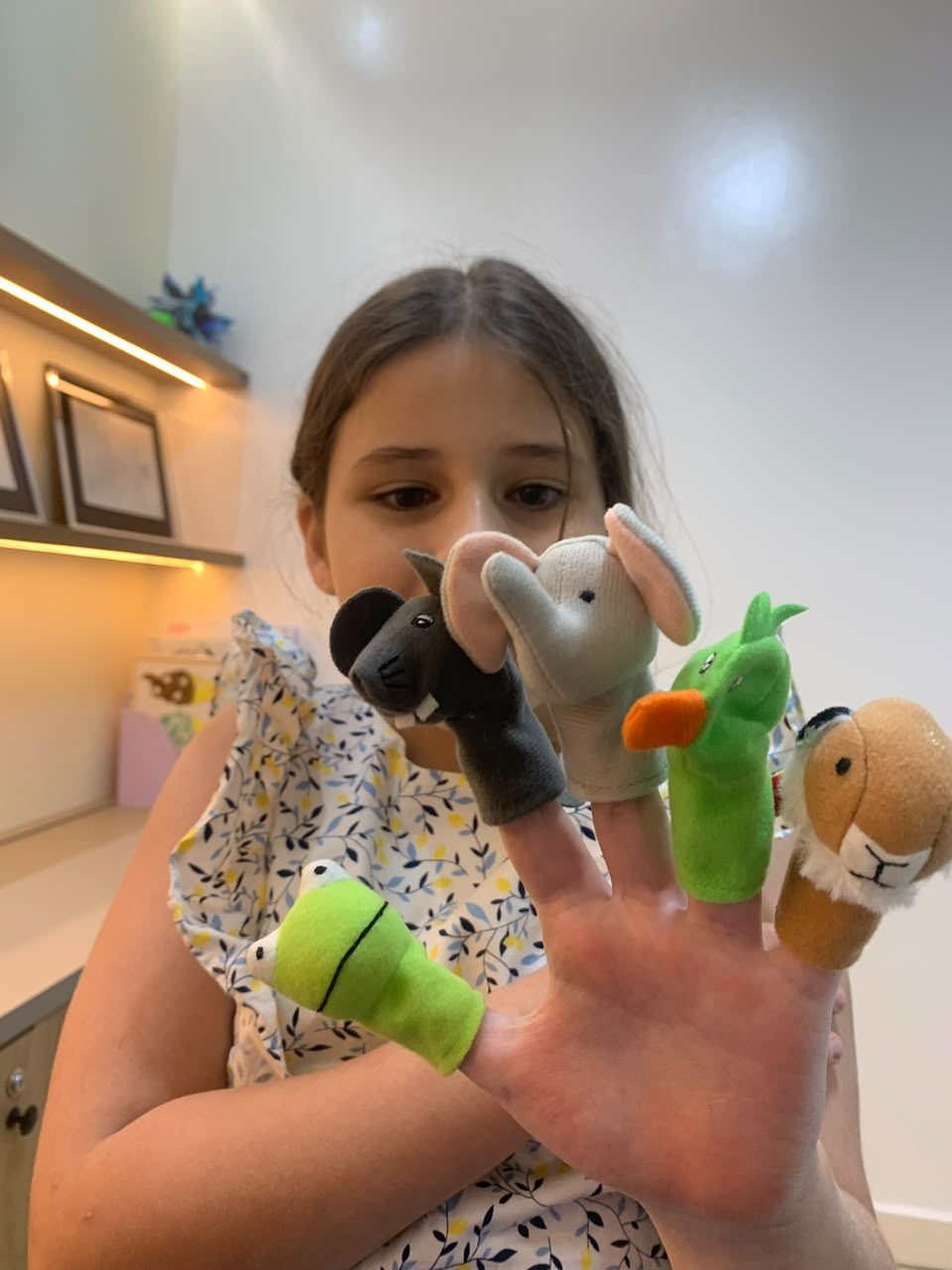 Una niña juega con títeres de dedo con forma de animales en el consultorio